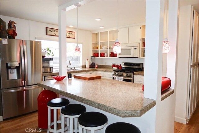 31351 Calle Del Campo, San Juan Capistrano, CA 92675 - kitchen featuring stainless steel appliances, light wood-type flooring, a breakfast bar area, open shelves, and white cabinets