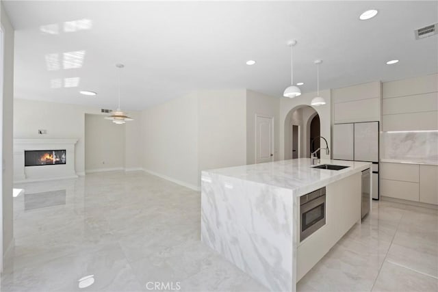 68 Sanctuary, Irvine, CA 92620 - kitchen featuring modern cabinets, light marble finish flooring, arched walkways, a sink, and recessed lighting
