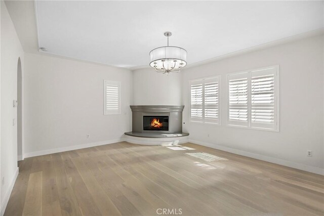 68 Sanctuary, Irvine, CA 92620 - unfurnished living room with hardwood / wood-style floors, baseboards, a chandelier, a glass covered fireplace, and arched walkways