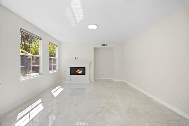 68 Sanctuary, Irvine, CA 92620 - unfurnished living room featuring light marble finish floors, a warm lit fireplace, and baseboards