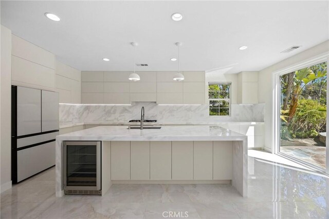 68 Sanctuary, Irvine, CA 92620 - kitchen featuring beverage cooler, modern cabinets, a sink, a large island, and fridge