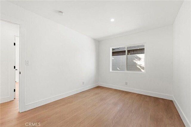 empty room featuring baseboards and light wood-type flooring