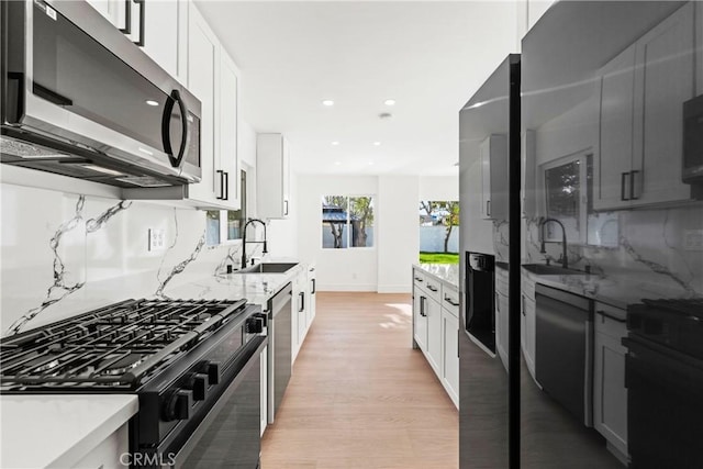 kitchen featuring light wood finished floors, a sink, white cabinets, and appliances with stainless steel finishes