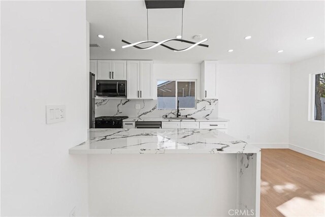 kitchen with backsplash, light stone countertops, a sink, and white cabinets