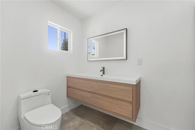 half bathroom featuring toilet, vanity, and baseboards