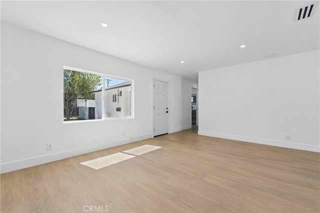 empty room featuring baseboards, light wood-style flooring, and visible vents