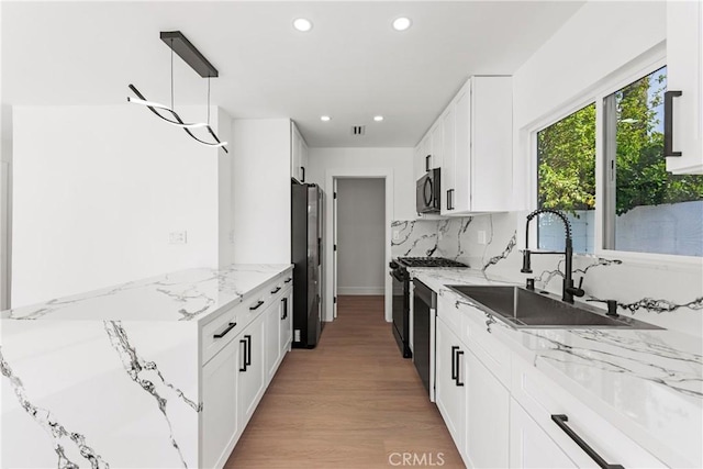 kitchen with white cabinetry, refrigerator with ice dispenser, backsplash, a sink, and black microwave