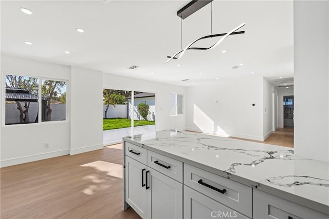 kitchen with visible vents, light stone countertops, recessed lighting, light wood-type flooring, and open floor plan