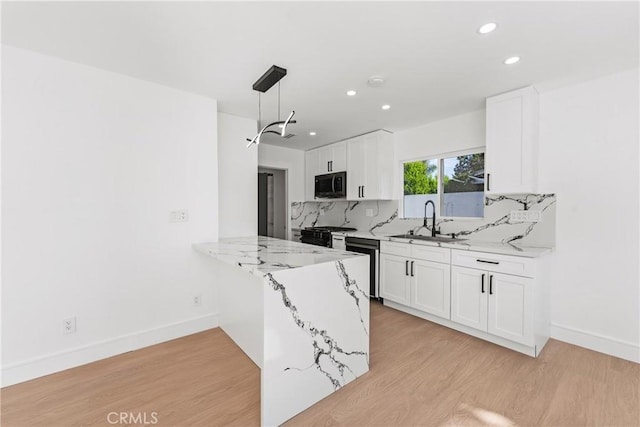 kitchen with a sink, black microwave, light wood finished floors, tasteful backsplash, and dishwasher
