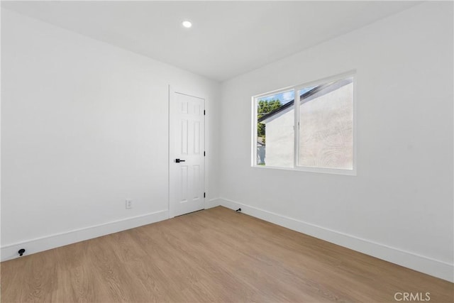 spare room featuring baseboards, light wood finished floors, and recessed lighting