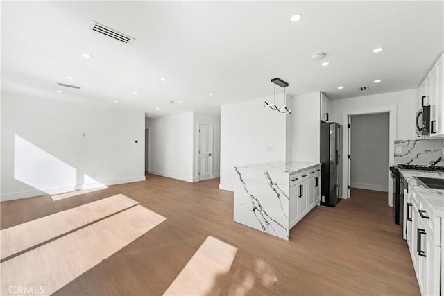 kitchen featuring light stone counters, light wood finished floors, visible vents, white cabinets, and black appliances