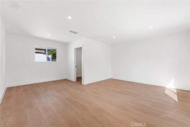 spare room with baseboards, light wood finished floors, and visible vents