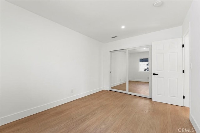 unfurnished bedroom featuring visible vents, a closet, baseboards, and light wood-type flooring