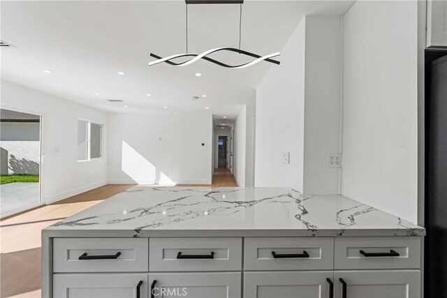 kitchen with light wood-style flooring, light stone counters, recessed lighting, and open floor plan