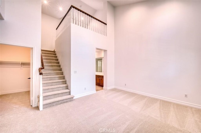 interior space with carpet floors, a high ceiling, baseboards, and stairs