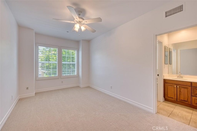 unfurnished bedroom with visible vents, a sink, baseboards, and light carpet
