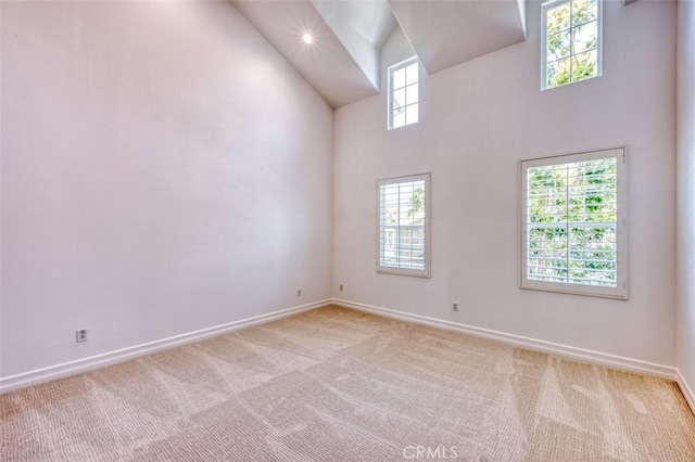 unfurnished room with baseboards, light carpet, and high vaulted ceiling