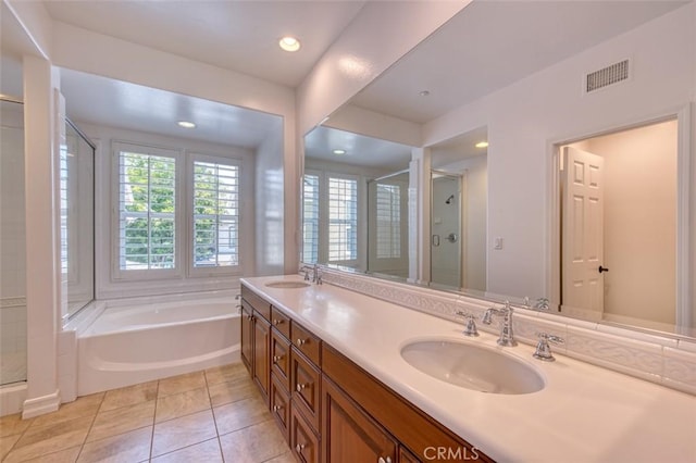 bathroom with visible vents, a garden tub, double vanity, a shower stall, and a sink