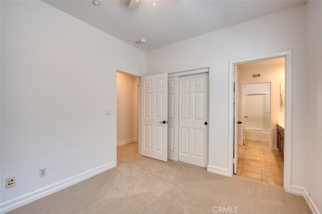 unfurnished bedroom with baseboards, visible vents, light carpet, and a closet