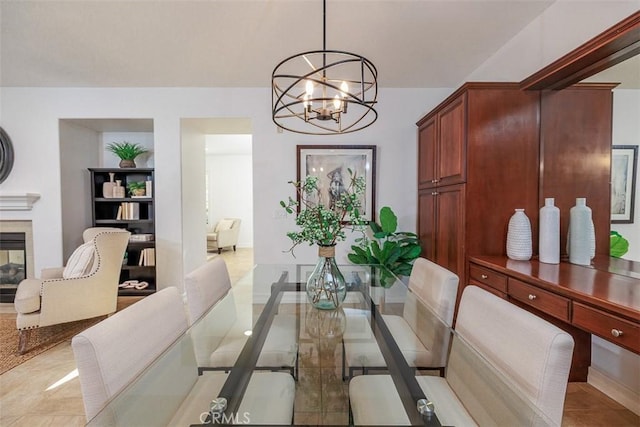 dining area featuring an inviting chandelier and a tiled fireplace