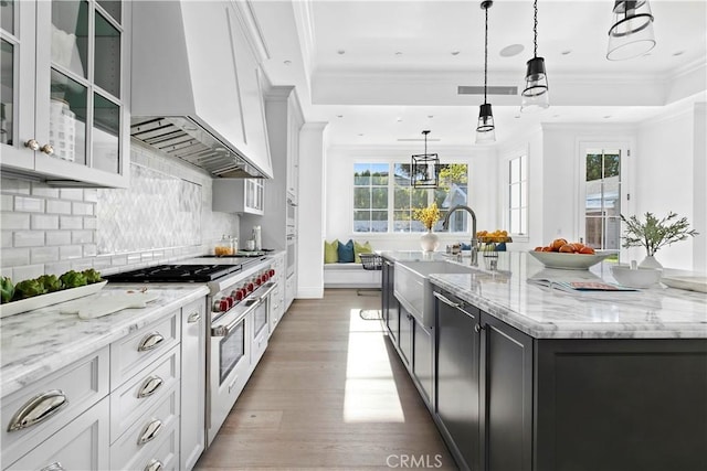 kitchen featuring light stone countertops, wall chimney exhaust hood, a spacious island, and double oven range