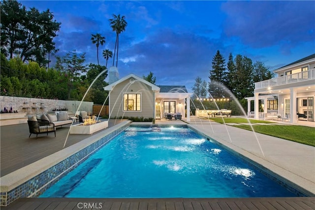 pool at dusk featuring an exterior structure, a fenced in pool, a deck, an outdoor living space, and an outdoor structure