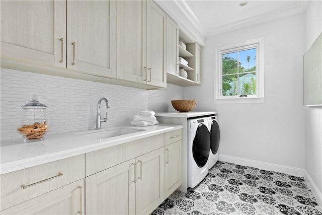 washroom with ornamental molding, baseboards, washing machine and clothes dryer, a sink, and cabinet space