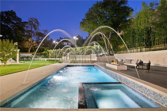 view of pool with outdoor lounge area, a pool with connected hot tub, fence, and a lawn