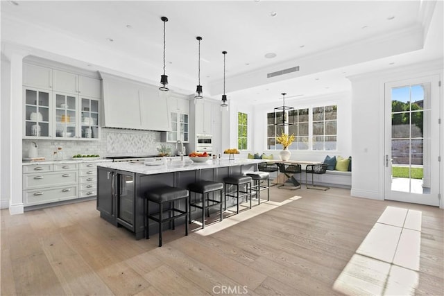 kitchen with a spacious island, backsplash, a kitchen bar, light wood-style floors, and ornamental molding