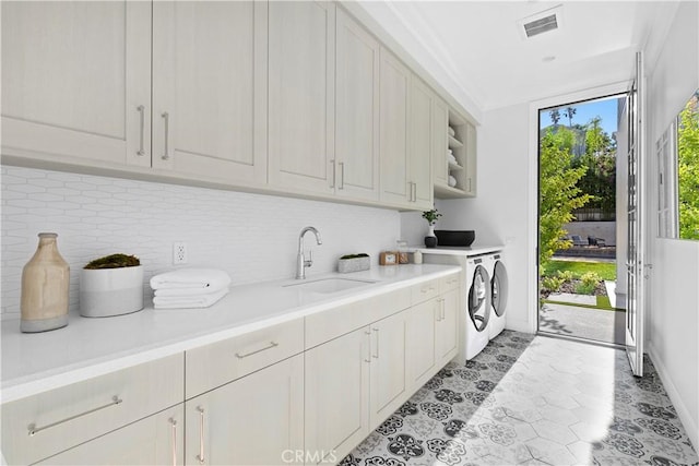 washroom with washing machine and clothes dryer, a sink, light tile patterned flooring, visible vents, and cabinet space