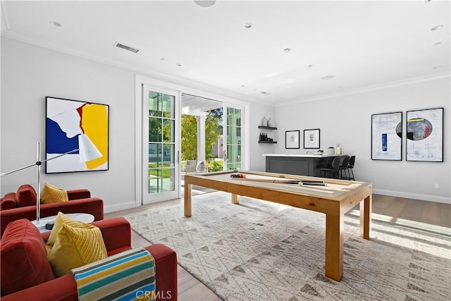 recreation room with visible vents, crown molding, baseboards, and wood finished floors