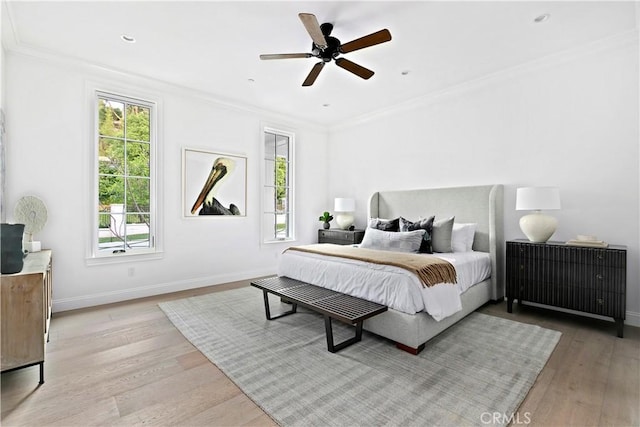 bedroom featuring baseboards, light wood-style flooring, ornamental molding, and a ceiling fan