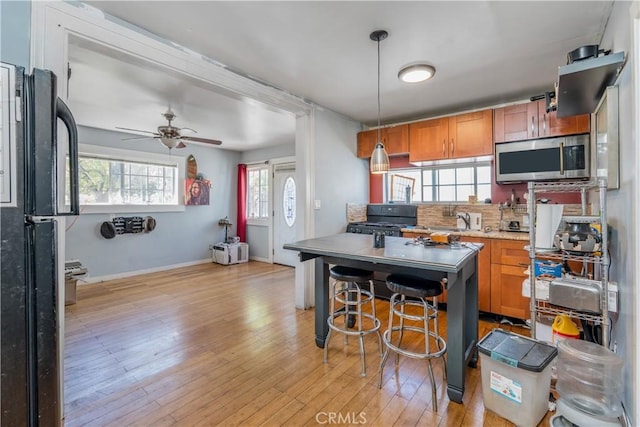 1361 W Vernon Ave, Los Angeles, CA 90037 - kitchen featuring ceiling fan, brown cabinets, light wood-type flooring, black appliances, and backsplash