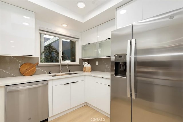 2405 Via Mariposa W Unit 1B, Laguna Woods, CA 92637 - kitchen with appliances with stainless steel finishes, a sink, white cabinetry, light countertops, and decorative backsplash