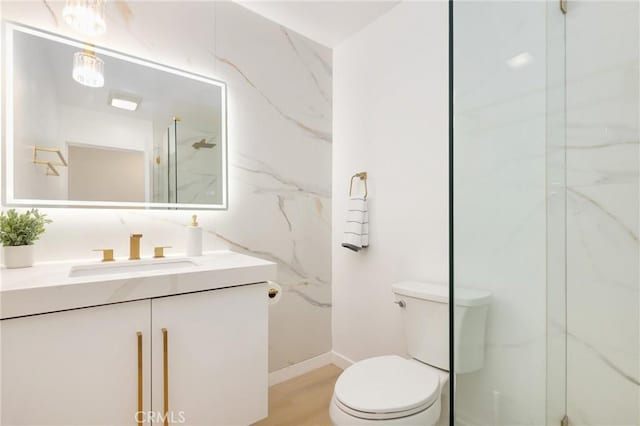 2405 Via Mariposa W Unit 1B, Laguna Woods, CA 92637 - bathroom featuring toilet, vanity, a marble finish shower, baseboards, and wood finished floors