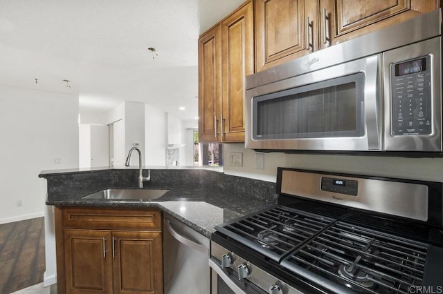 11365 Affinity Ct Unit 192, San Diego, CA 92131 - kitchen featuring appliances with stainless steel finishes, a peninsula, dark stone countertops, wood finished floors, and brown cabinetry