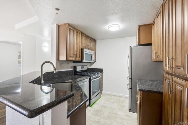 11365 Affinity Ct Unit 192, San Diego, CA 92131 - kitchen featuring stainless steel appliances, a peninsula, brown cabinets, dark stone counters, and a textured ceiling