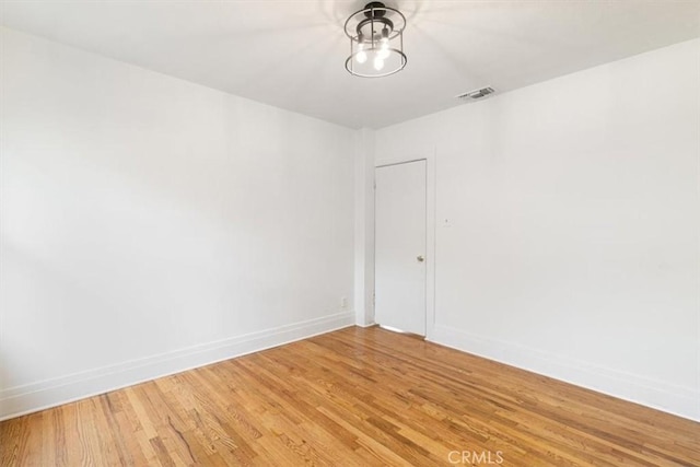 spare room featuring baseboards, visible vents, and light wood-style floors