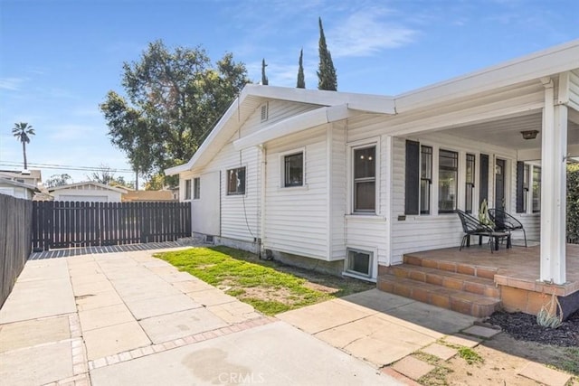 view of property exterior with covered porch and fence