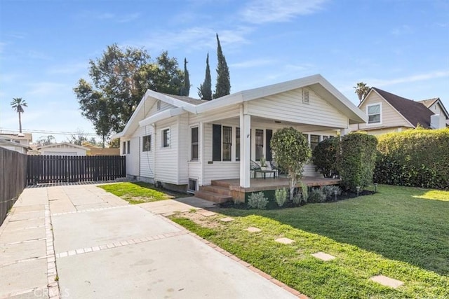 view of front of house with driveway, a front yard, covered porch, and fence