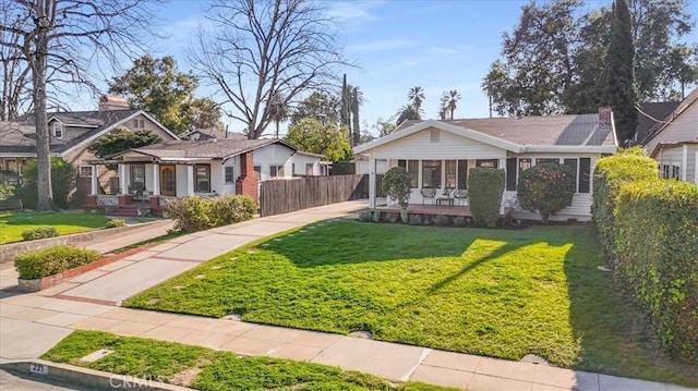 view of front facade with covered porch, fence, a front lawn, and a residential view