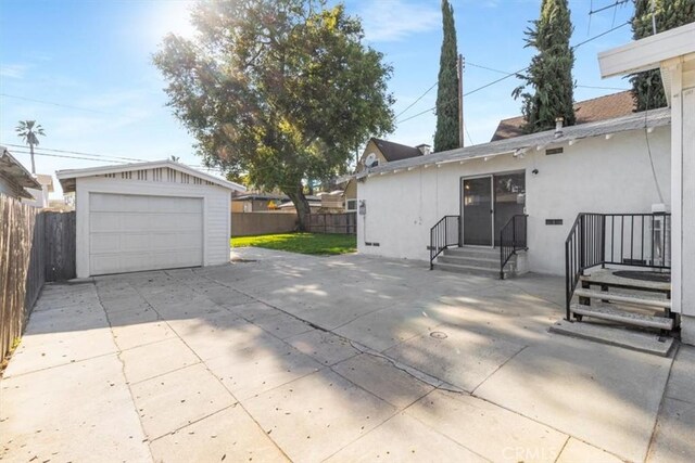 exterior space featuring an outdoor structure, driveway, a garage, and fence