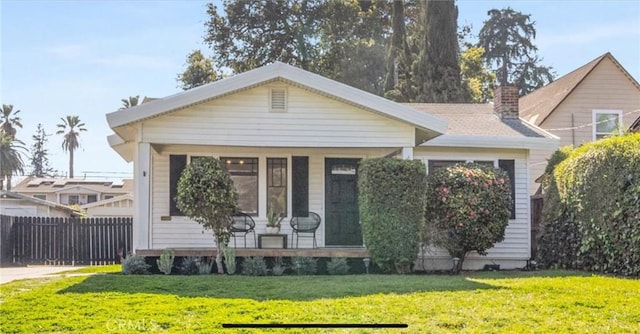 view of front of property with a chimney, fence, and a front lawn
