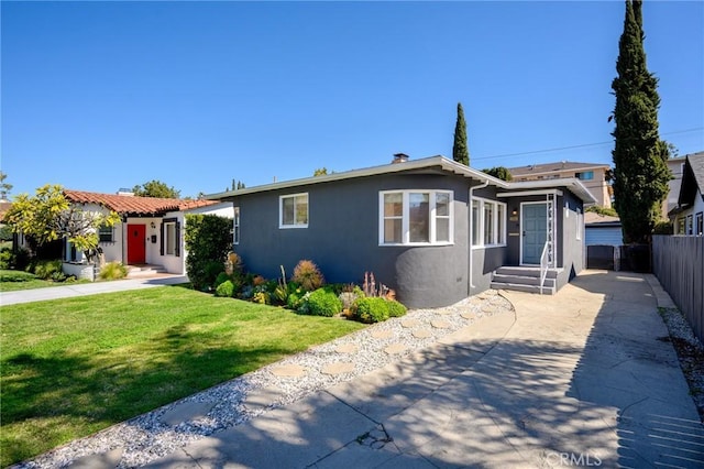 view of front of house with stucco siding, fence, and a front lawn