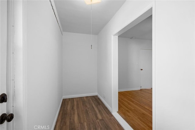 corridor featuring dark wood-style flooring and baseboards