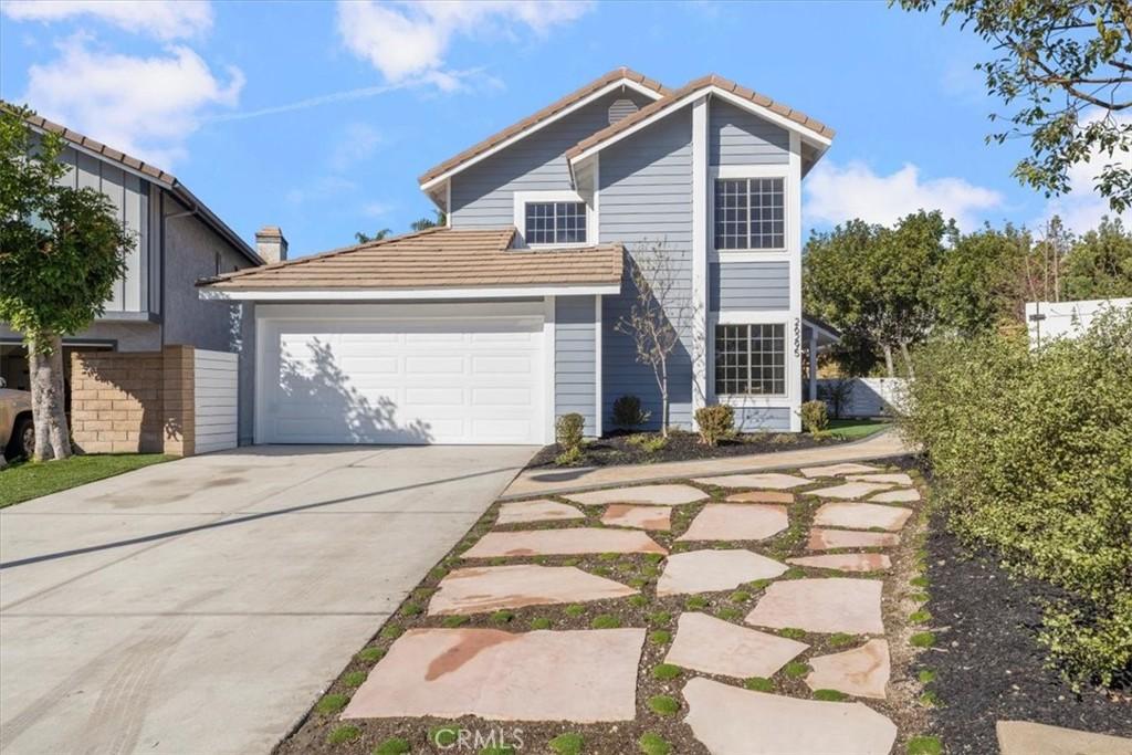 traditional-style house with a tile roof, driveway, and an attached garage