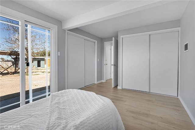bedroom with visible vents, two closets, baseboards, light wood-type flooring, and access to outside