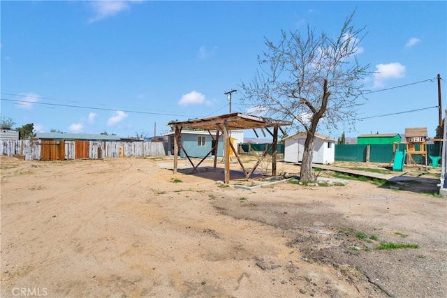 view of yard featuring a storage shed, fence, an outbuilding, and a playground