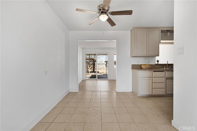 kitchen with a sink, dark countertops, baseboards, a ceiling fan, and light tile patterned floors