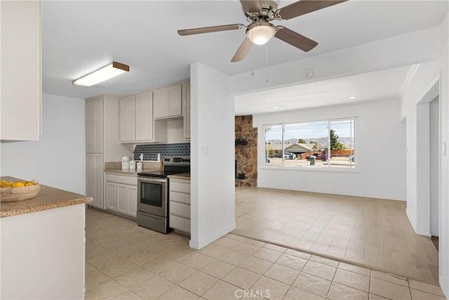 kitchen featuring a ceiling fan, backsplash, light tile patterned floors, light countertops, and electric stove